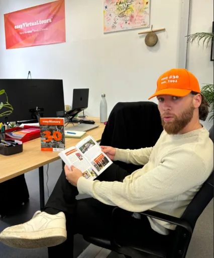 Un collaborateur casquette easy sur la tête feuillette le livre easyHistory au bureau