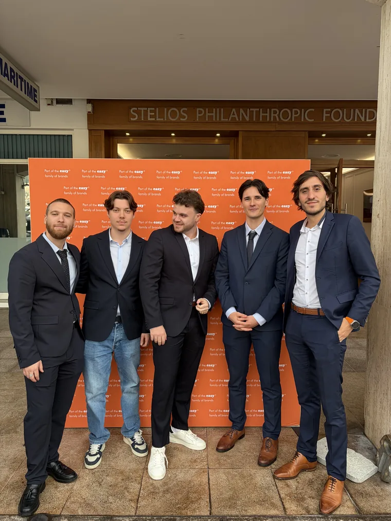 Cinq membres de l'équipe en costume devant le mur « Part of the easy family of brands »