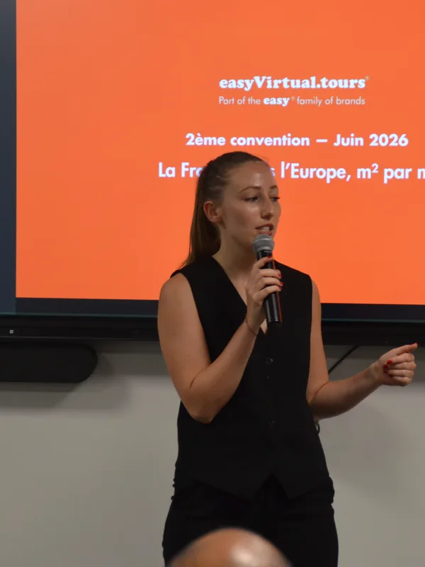 Une collaboratrice prend la parole au micro devant l'écran de la convention