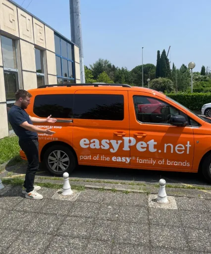 Un collaborateur ouvre le hayon d'un utilitaire orange easyPet.net avant une captation