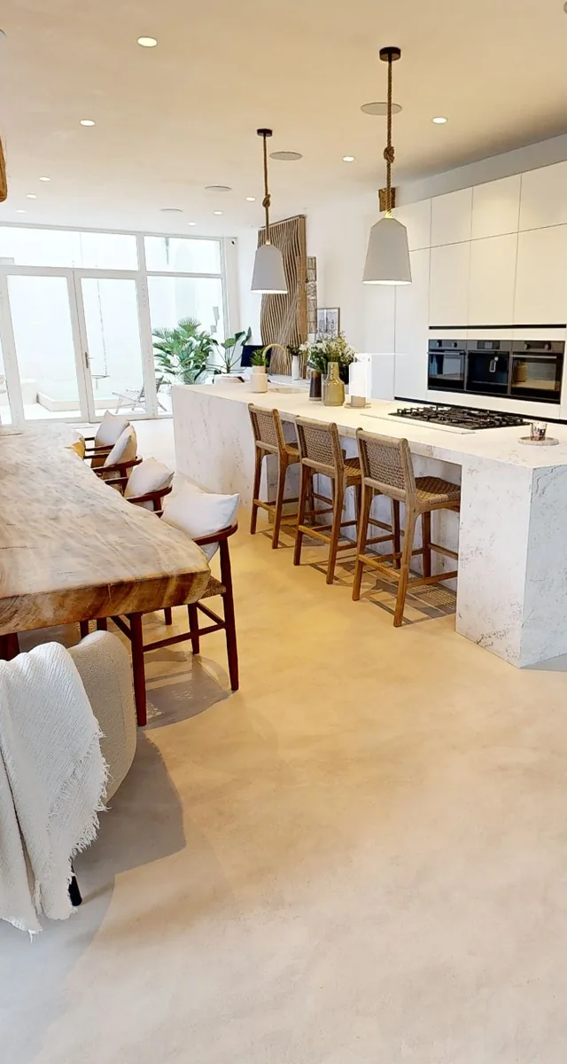 Open-plan kitchen in a loft with an island and a large table, seen in the tour