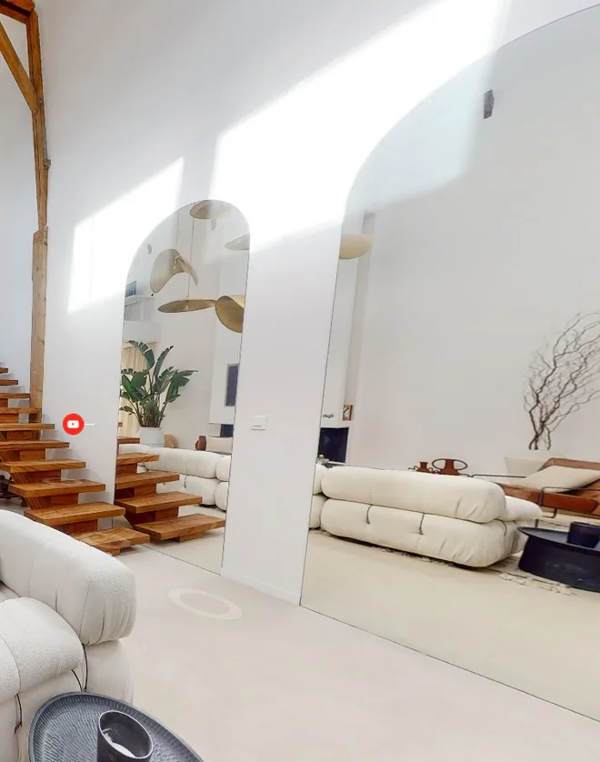 Bright living room with a wooden staircase, seen in a virtual tour