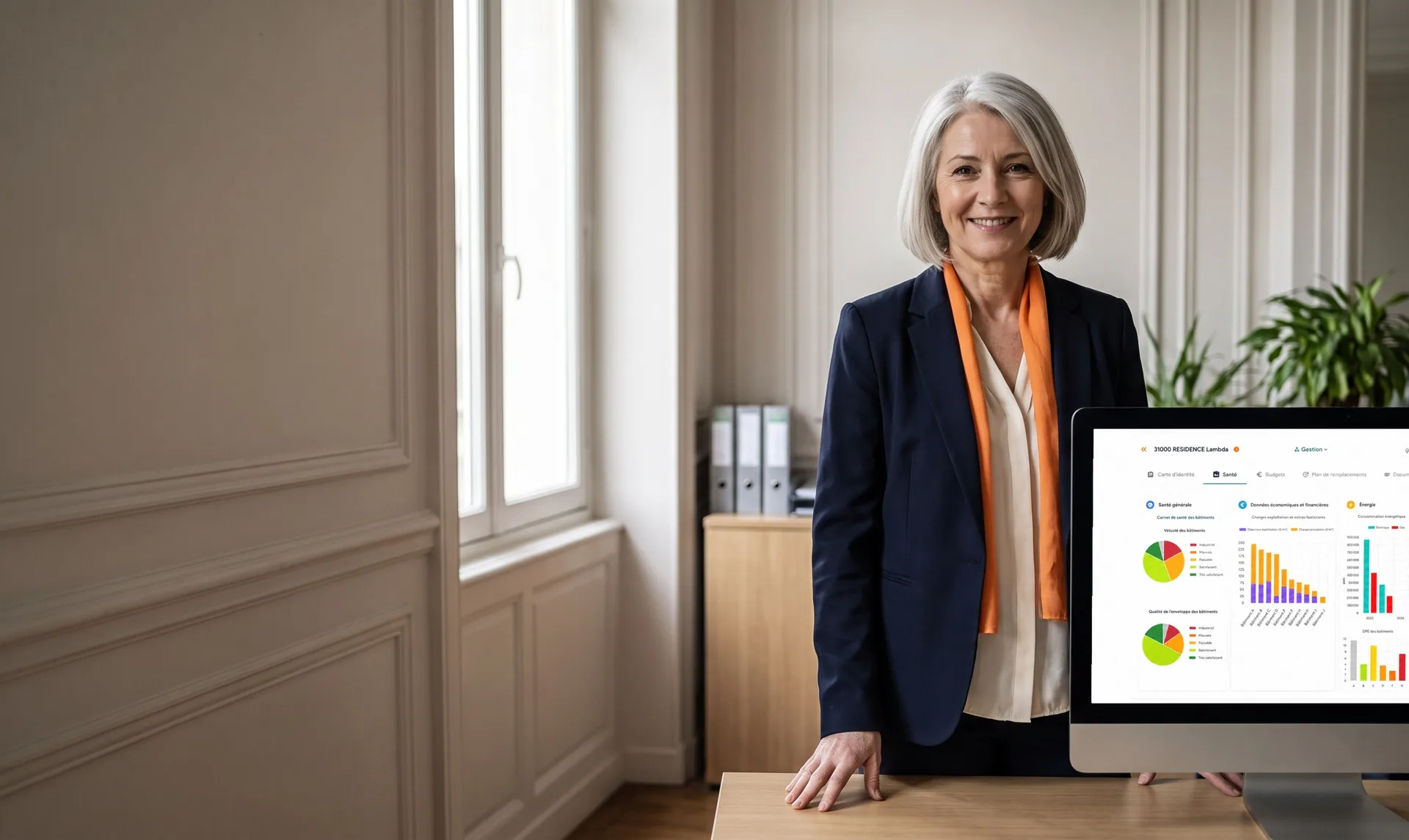 Council head of property at their desk, in front of a screen showing the building health record for the council's buildings