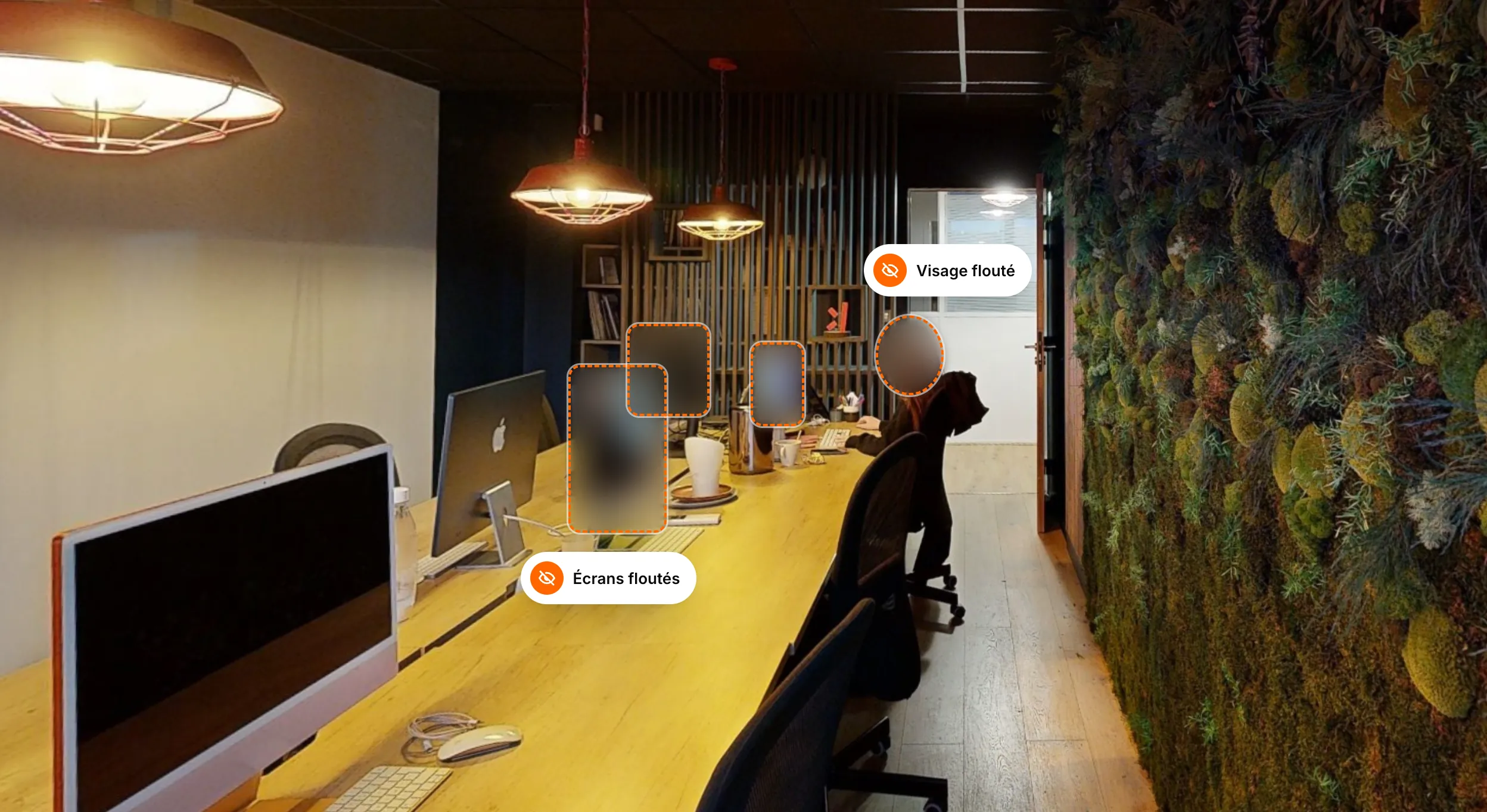 An open-plan office seen in its virtual tour on a tablet, with a colleague's face and three screens blurred