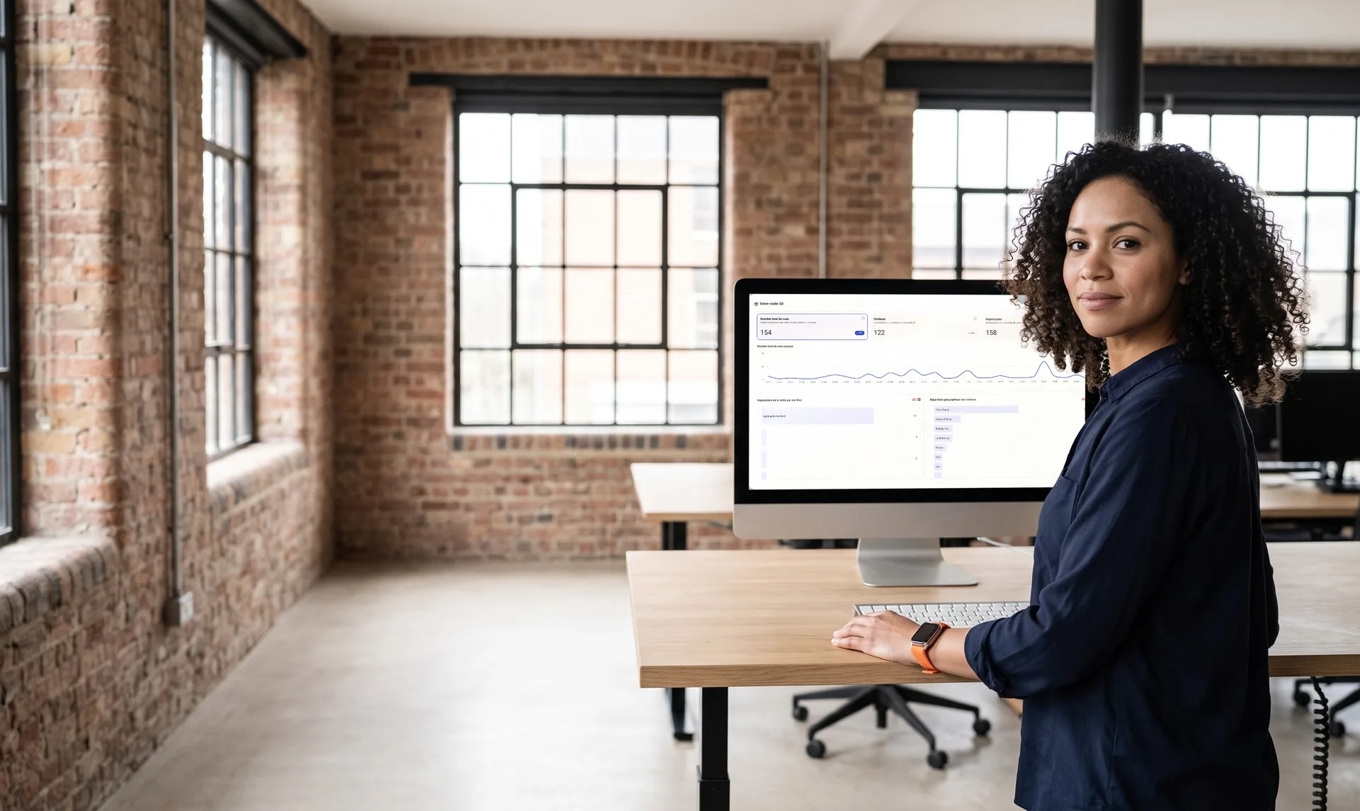 Marketing manager at her desk, in front of a screen showing a virtual tour's views chart over 30 days
