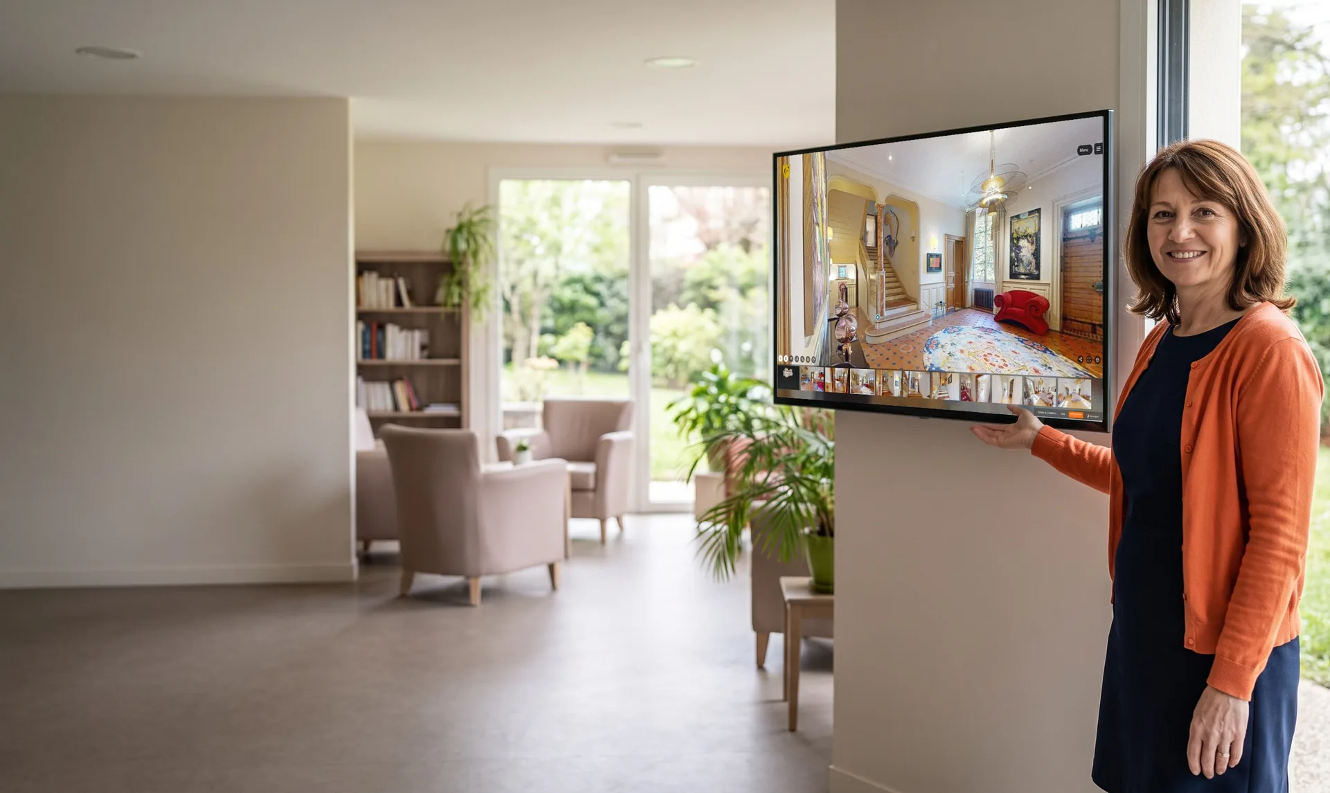 Manager of a retirement residence beside a wall screen playing an automatic guided tour