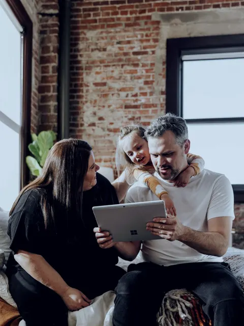 A family looks at a tablet together in a living room