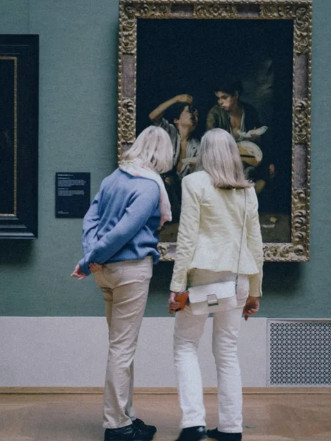 Two visitors look at a painting in a museum